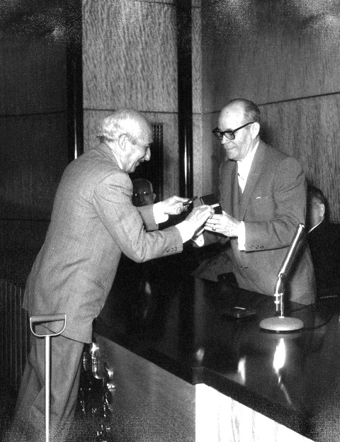 Foto de Villanueva recibe de manos del historiador Emeterio Santovenia la medalla conmemorativa de la inauguración del nuevo edificio de la Biblioteca Nacional José Martí, febrero de 1958. Colección de fotografías BNJM.